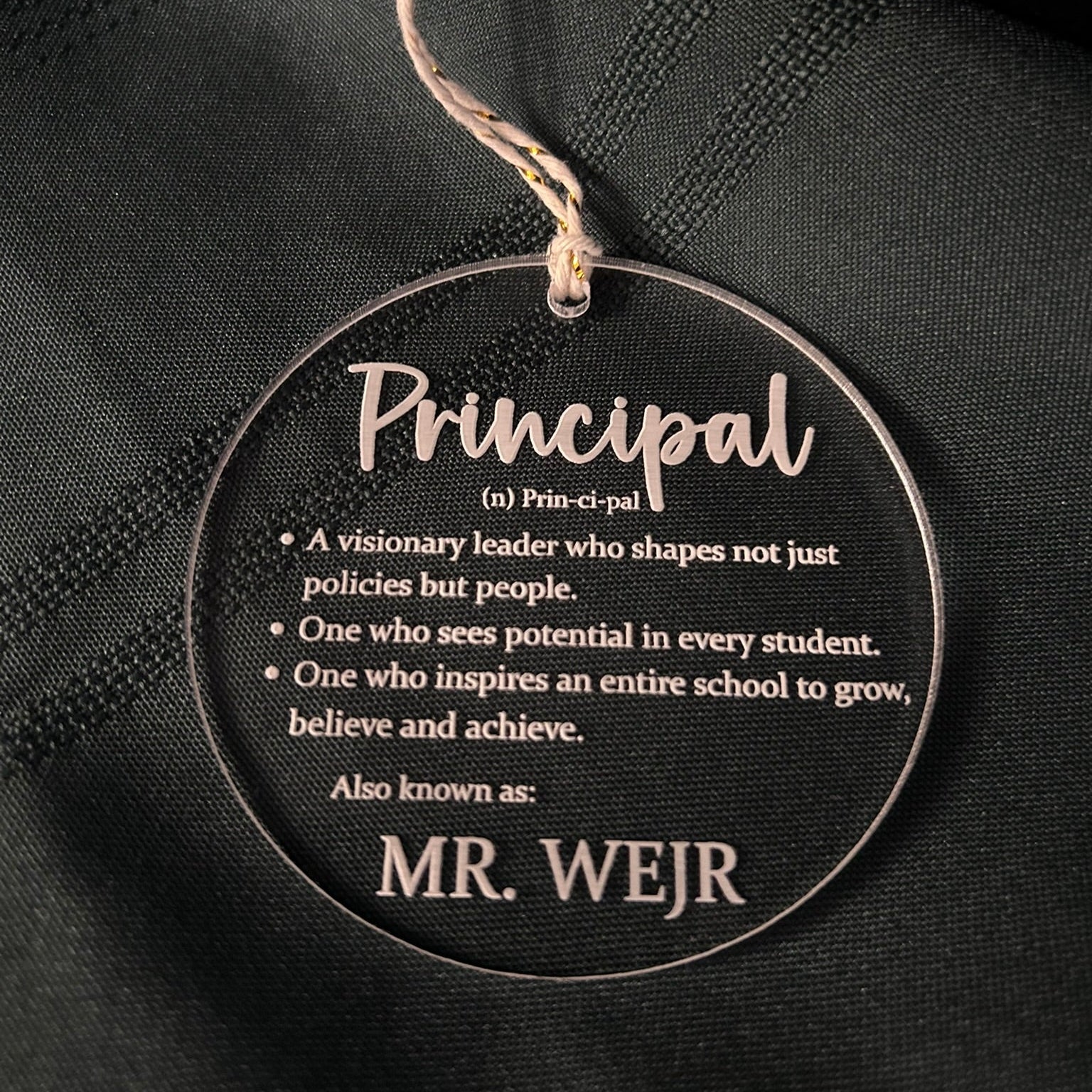 Round decorative tag with definition of 'Principal' on a black background