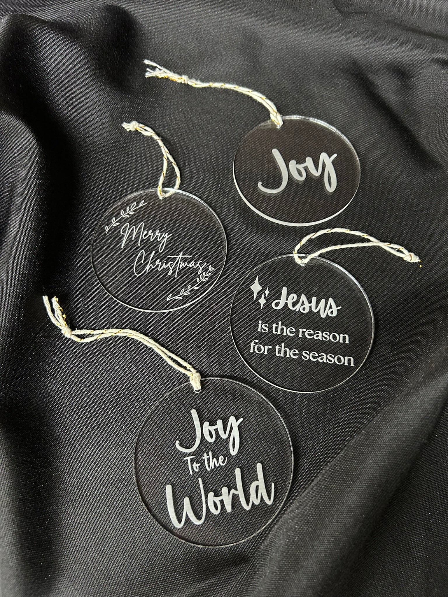 Set of Christmas-themed glass ornaments with text on a black fabric background