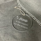 Decorative tag with 'Jesus is the reason for the season' text on a gray fabric background