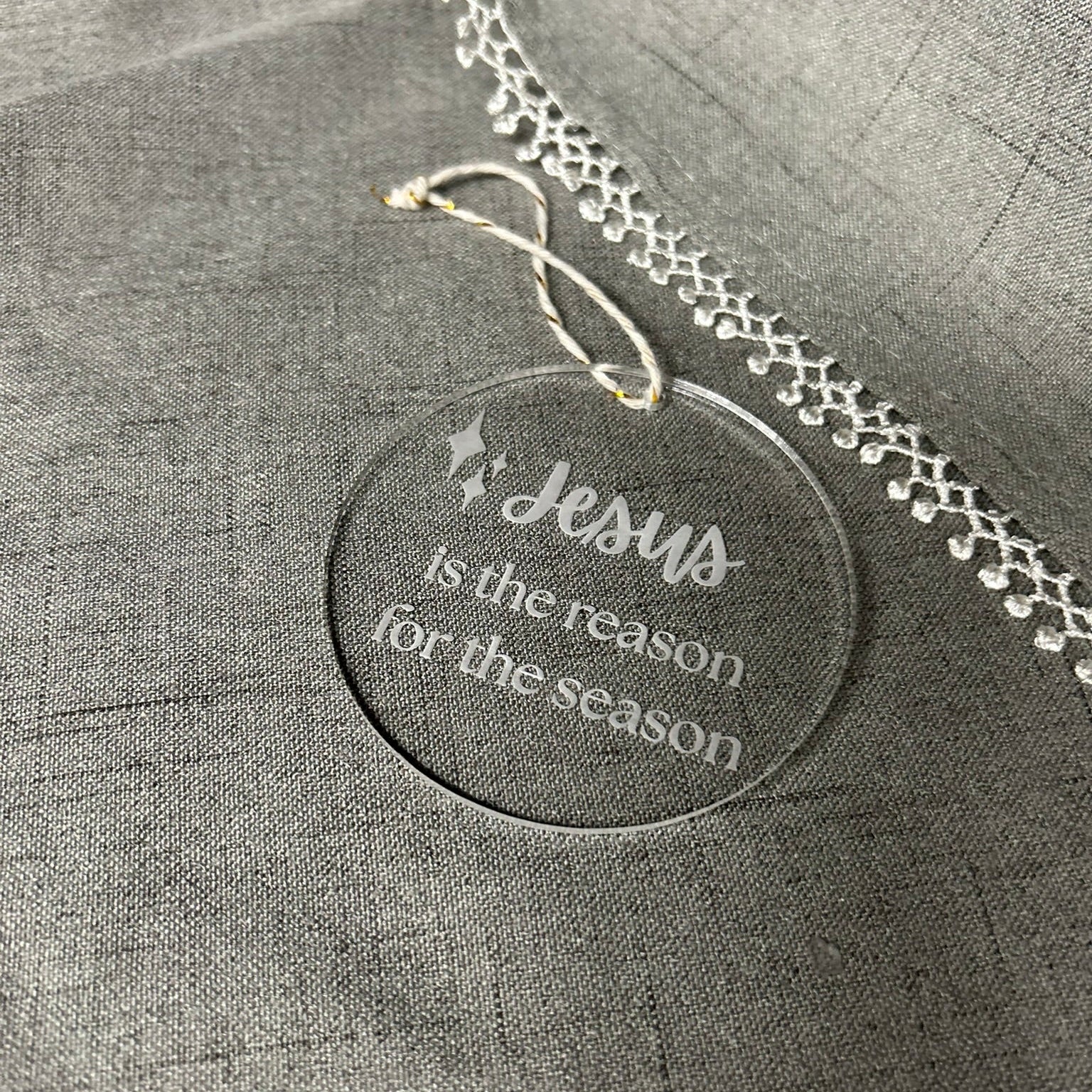 Decorative tag with 'Jesus is the reason for the season' text on a gray fabric background