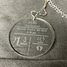 Necklace with a round pendant displaying engraved text on a gray fabric background