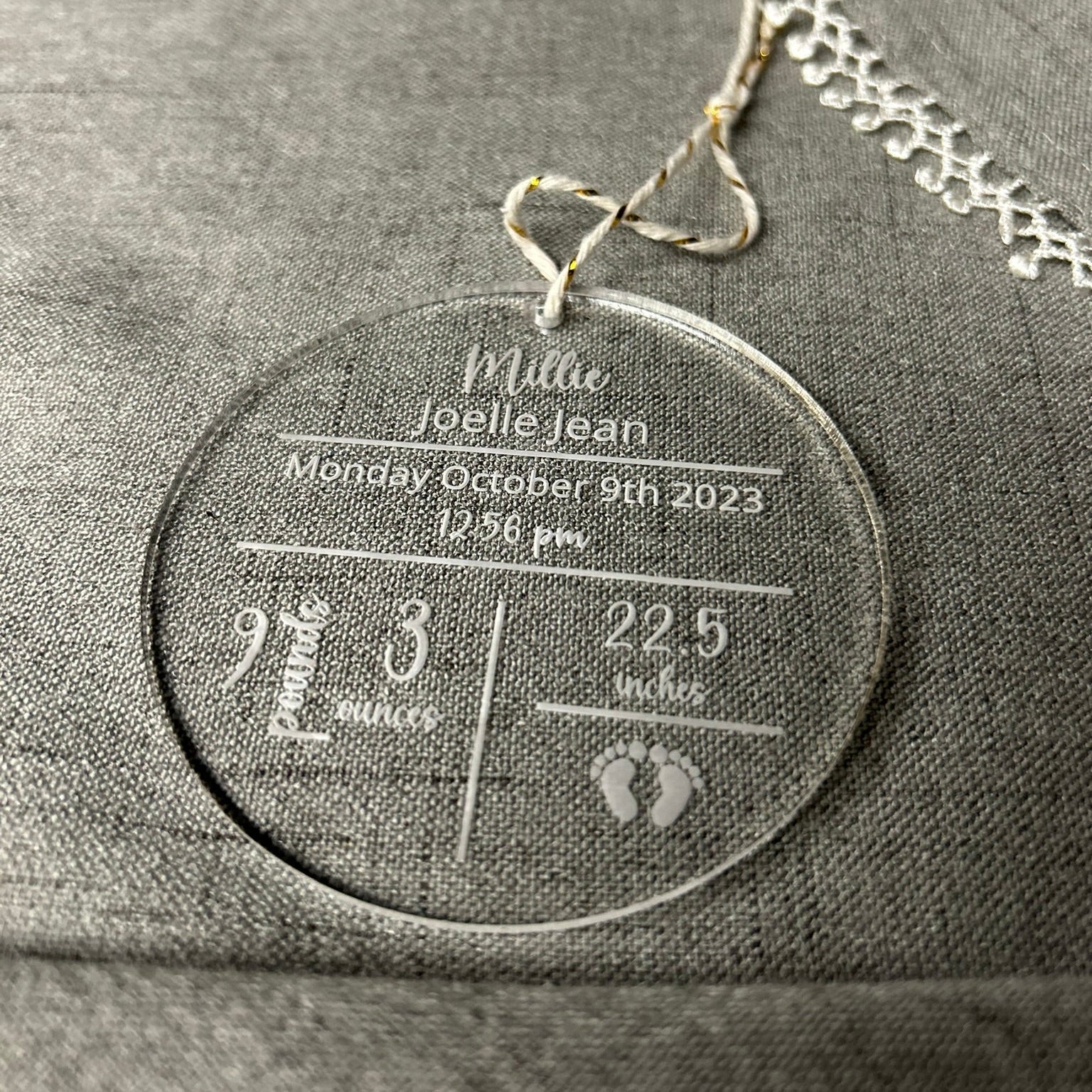Necklace with a round pendant displaying engraved text on a gray fabric background