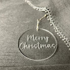 Silver necklace with a 'Merry Christmas' pendant on a textured gray surface
