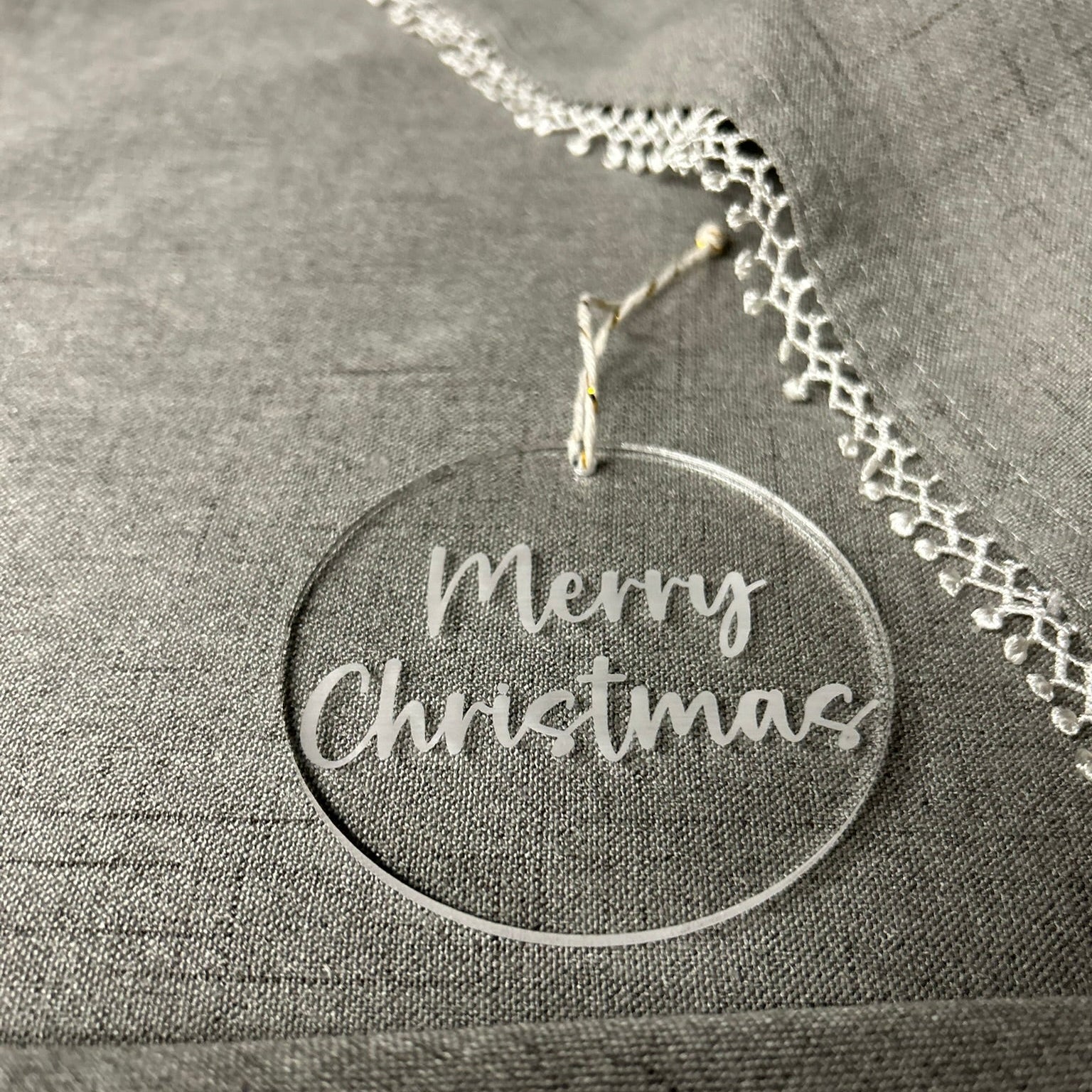 Silver necklace with a 'Merry Christmas' pendant on a textured gray surface